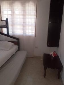 Un dormitorio con una cama y una mesa con flores. en Cabana De Descanso, Isla De Baru - Cartagena - Rest Cabin, Baru Island -Bolivar, en Playa Blanca