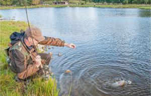 um homem sentado na água com um peixe na água em Gorgeous Home In Hrby With House Sea View em Hörby