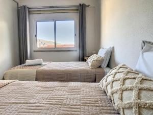 deux lits dans une chambre avec une fenêtre dans l'établissement Casa Pico dos Barcelos by LovelyStay, à Funchal