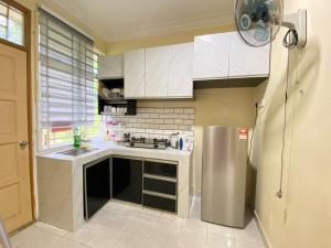 a kitchen with white cabinets and a stainless steel refrigerator at Naufa Homestay 2 3R3B Machang in Macang