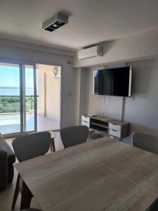 sala de estar con mesa de madera y TV de pantalla plana en Departamento Ribera en Ramallo