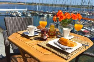 einen Tisch mit Speisen, Getränken und Blumen auf dem Balkon in der Unterkunft Yachthafenblick in Heiligenhafen