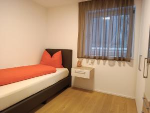 una camera da letto con un letto con lenzuola arancioni e una finestra di Zum Lindenwirt - Al Tiglio a Naz-Sciaves