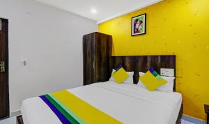 a bedroom with a white bed with a yellow wall at Itsy By Treebo - Harsha Comforts in Chikmagalūr