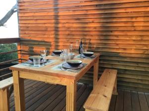 einem Holztisch mit Schalen und Gläsern auf einer Terrasse in der Unterkunft Gîte rural _ vue Océan _ des bateaux dans le ciel in Saint-Denis