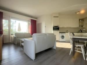ein Wohnzimmer mit weißen Möbeln und eine Küche in der Unterkunft Wijk de Brabander 62 in Cadzand