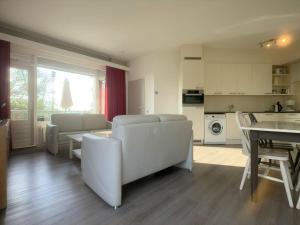 a living room with white furniture and a kitchen at Wijk de Brabander 62 in Cadzand