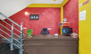 an office with a desk and a red wall at Itsy By Treebo - Harsha Comforts in Chikmagalūr