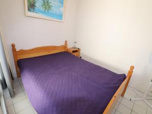 uma cama com um edredão roxo num quarto em Appartement Le Grau-du-Roi, 2 pièces, 4 personnes - FR-1-307-11 em Le Grau-du-Roi