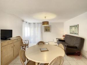 uma sala de estar com uma mesa e um sofá em Appartement Lamalou-les-Bains, 2 pièces, 2 personnes - FR-1-451-24 em Lamalou-les-Bains