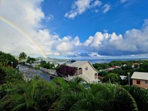 a rainbow in the sky over a town with a house at SERENITY piscine au sel in La Trinité