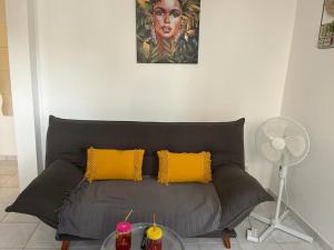 a black couch with two yellow pillows in a living room at Résidence Flores De Maria in Le Marin