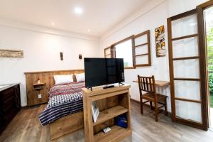 1 dormitorio con 1 cama y TV de pantalla plana en Casa Lucas - loft espaçoso com jardim e churrasqueira, en Petrópolis