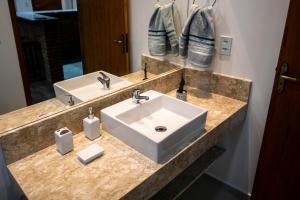 Un baño con un lavabo blanco y un espejo. en Casa Lucas - loft espaçoso com jardim e churrasqueira, en Petrópolis 9 fotos más