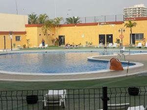 a large swimming pool in a building with people sitting around it at Happy Space Apartment in Los Cristianos