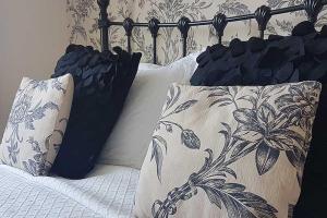 a bed with black and white pillows on it at The Coast Yard B & B and Garden Chalets in Chichester
