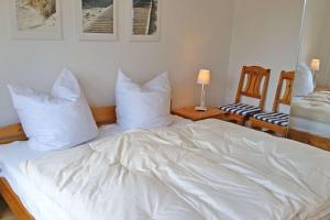 un letto con lenzuola e cuscini bianchi in una stanza di Kapitäns-Hus a Heiligenhafen