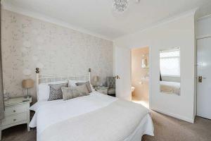 a white bedroom with a large bed and a bathroom at The Coast Yard B & B and Garden Chalets in Chichester