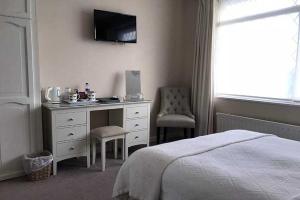 a bedroom with a bed and a desk and a television at The Coast Yard B & B and Garden Chalets in Chichester