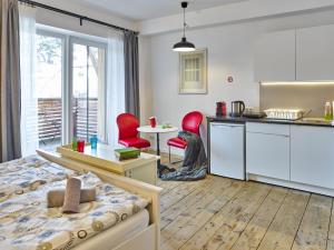 a bedroom with a bed and a kitchen with red chairs at Innheaven Apartments in Innsbruck