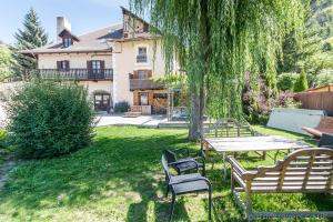 a picnic table and chairs under a tree in a yard at Luxury Chalet with outdoor Hot Tub, Sauna, Gardens & Mountain Views! in Briançon