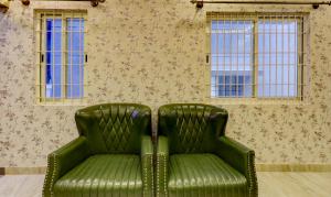 a green leather chair in front of a wall with windows at Treebo Trend Three Street Inn in Bangalore