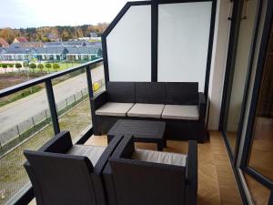 uma varanda com 2 cadeiras, uma mesa e uma janela em Apartamenty AMBER -Marina Dziwnów - basen, jacuzzi i sauny em Dziwnów