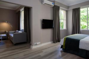 ブエノスアイレスにあるSuMa Recoleta Hotelのベッド、ソファ、テレビが備わるホテルルームです。