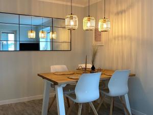 a dining room with a wooden table and white chairs at Ferienwohnung Watt'n Weitblick in Simonsberg