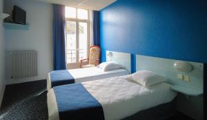 two beds in a room with a blue wall at Le CESAR HOTEL in Royat