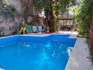 a swimming pool with blue water in a backyard at Posada Chalet de Bassi in Mendoza