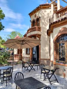 eine Außenterrasse mit Tischen, Stühlen und einem Sonnenschirm in der Unterkunft Posada Chalet de Bassi in Mendoza