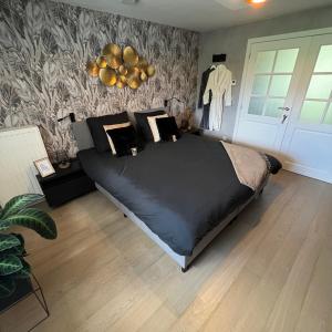 a bedroom with a large black bed with a wall at Bed & Bokes aan de Maaskant in Lanaken