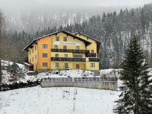 a large yellow building with snow on the ground at Hotel Ötscherblick in Lackenhof