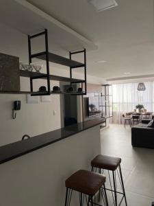 cocina y sala de estar con 2 taburetes y barra en Apartamento vista mar em João Pessoa, en João Pessoa