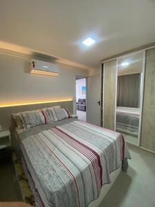 1 dormitorio con 1 cama con manta a rayas en Apartamento vista mar em João Pessoa, en João Pessoa