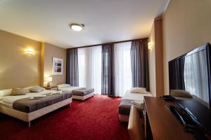 a hotel room with two beds and a flat screen tv at Apartamenty-Europejska in Suwałki