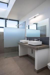 baño con 2 lavabos y espejo grande en Hilltop Bayview Luxury Apartments, en Plettenberg Bay