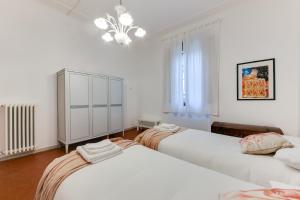 フォルリにあるRomagnaBNB Campostrinoのベッドルーム1室(ベッド2台、キャビネット、シャンデリア付)