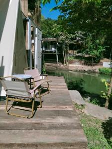 2 sillones y una mesa en un muelle de madera en Brook Cottage en Ban Khanong Phra Klang (1)