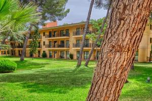 an apartment building with palm trees in a park at Caprice Vell Mari Hotel & Resort - New Opening 2026 in Can Picafort