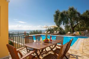a wooden table and chairs next to a swimming pool at Villa Kalithea in Nisaki