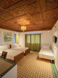 1 dormitorio con 2 camas y techo de madera en Desert Villa Boutique Hotel Merzouga, en Merzouga