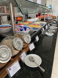 una línea de buffet con platos y cucharas en un mostrador en Nobile Inn Dutra Rio De Janeiro, en São João de Meriti