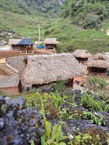 Homestay Highland Hmong في Hòa Bình: مجموعة من الأكواخ بأسطح من القش على تلة
