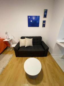 ein Wohnzimmer mit einem schwarzen Sofa und einem weißen Tisch in der Unterkunft Monoambiente Evans in Ciudad Lujan de Cuyo