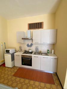 uma cozinha com armários brancos e um forno com placa de fogão em Lo Bec em Ronco Canavese