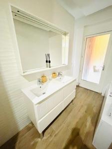 uma casa de banho branca com um lavatório e um espelho em Bonaparte em Nice