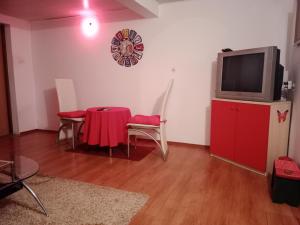 a living room with a red table and a tv at Blossom Cottage - Sustainable Tourism Retreat in Laktaši