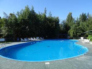una gran piscina azul con sillas y árboles en Cabañas Parque Salto del Laja en El Manzano